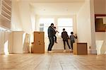 Mid adult man and three children looking from window of new home