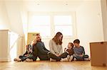 Mid adult couple and three children sitting on floor in new home