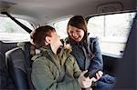 Boy and sister laughing in car backseat