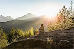 Woman sitting on rocks, looking at view, rear view, Squamish, British Columbia, Canada