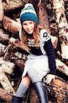 Portrait of young girl, sitting on log pile