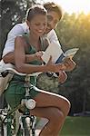 Young couple sitting on bicycle, looking at guidebook, Turin, Piedmont, Italy