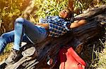 Young woman lying on fallen tree, Cape Town, South Africa