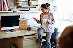 Woman sitting on desk looking at notepad