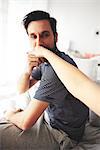 Man sitting on bed, kissing woman's hand