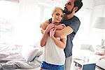 Couple in bedroom, wearing pyjamas, hugging