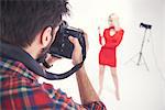 Over shoulder view of male photographer photographing female model on studio white background