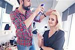 Male hairdresser putting hairspray on model for photo shoot