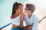 Young woman with finger on boyfriend's lips at poolside, Koh Samui, Thailand