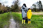 Rear view of woman with son in yellow anorak standing in park