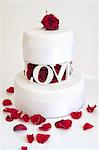 A two tier wedding cake with with red rose petals