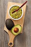 Guacamole and a fresh avocado on a chopping board