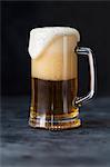 A glass of beer with overflowing foam