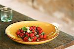 Freshly picked strawberries on a plate on a wooden table outside