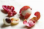 Lychees, peeled and opened with shells on a white surface