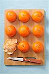 Whole mandarins and a peeled mandarin on a wooden board