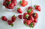 Freshly washed strawberries in glasses on a white wooden surface