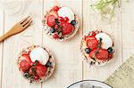 Strawberry tartlets with blueberries, redcurrants and cream (seen from above)