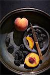 Fresh peaches and blackberries with a knife in a vintage colander