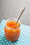 A jar of pumpkin and orange marmalade with a spoon