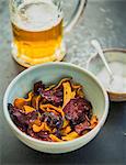 Colourful vegetable crisps (carrots, parsnips and beetroot) with salt and a beer