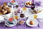 A table laid for breakfast with a purple tablecloth and white plates