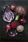 An arrangement of vegetables featuring artichokes, red onions, red cabbage and beetroot