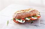 A baguette with mozzarella, tomato, pesto and rocket