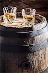 Two glasses of whisky with ice on an old wooden barrel