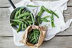 Pea pods in a sack and in a saucepan on a cloth