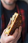 A man holding a ham and cheese toasty