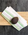 A whole avocado on a fabric napkin (seen from above)