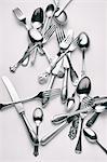 Various forks, knives and spoons on a white surface