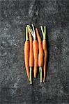 Five baby carrots next to each other on a grey surface