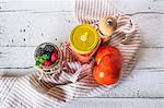 Cold tomato soup in a jar next to muesli with a jar of berries (seen from above)