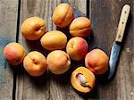 Fresh apricots with a kitchen knife on a wooden surface