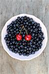 Blueberries and a pair of cherries in a bowl