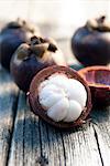 Mangosteen, whole and cut open, on a wooden table