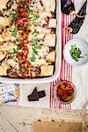 Enchiladas with pork and mole sauce in a baking dish with pickled jalapenos