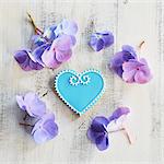 Heart-shaped biscuits decorated with blue and white icing and surrounded by flowers