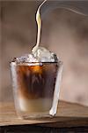 Sweetened condensed milkbeing poured into a glass of Vietnamese iced coffee