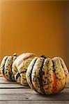 An arrangement of three pumpkins against an orange background