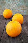 Three oranges on a wooden surface