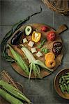 Fresh garden vegetables and corn on the cob on a wooden plate