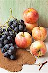 Black grapes, organic apples and an autumn leaf