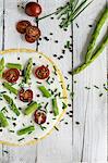 A tortilla pizza with cream cheese, asparagus, chives and tomatoes