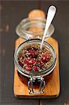 Pickled kalamata olives with oregano in glass jar on a chopping board