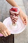 Hands holding a plate with a glass of raspberry & chocolate smoothie