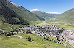 The alpine village of Andermatt surrounded by green meadows, and snowy peaks in the background, Canton of Uri, Switzerland, Europe