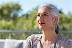 Portrait pensive, serious mature woman looking away on sunny patio